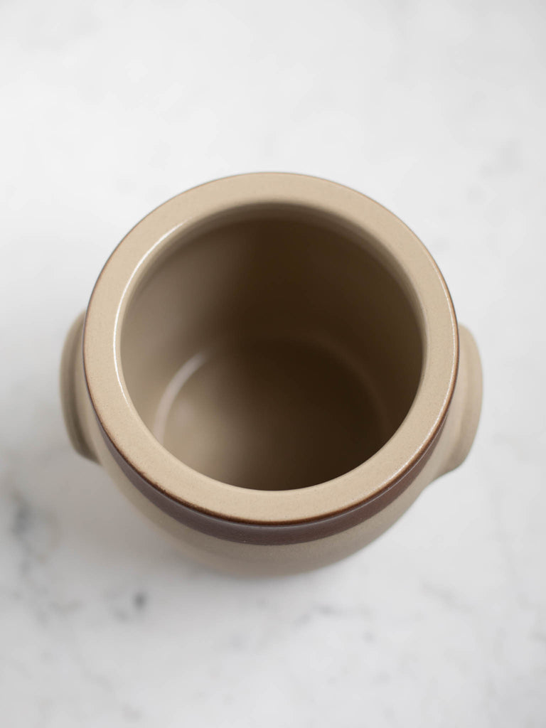 The inside of a white barrel crock with a brown rim. 