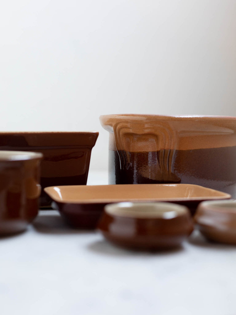 Bread pans, butter dishes, and small bowls all on top of a table. 