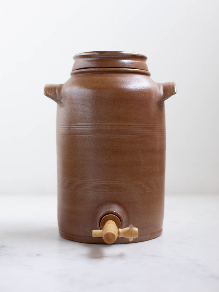 Tall light brown water jug with built in handles. 