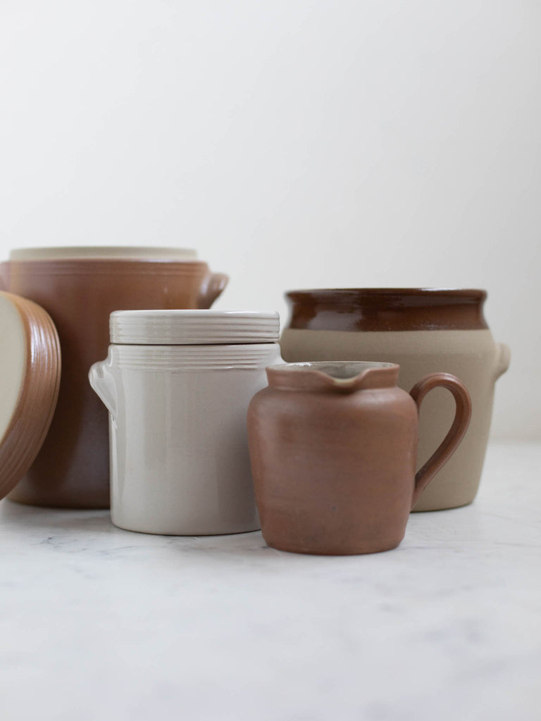 Various storage jars by a sauce pot. 