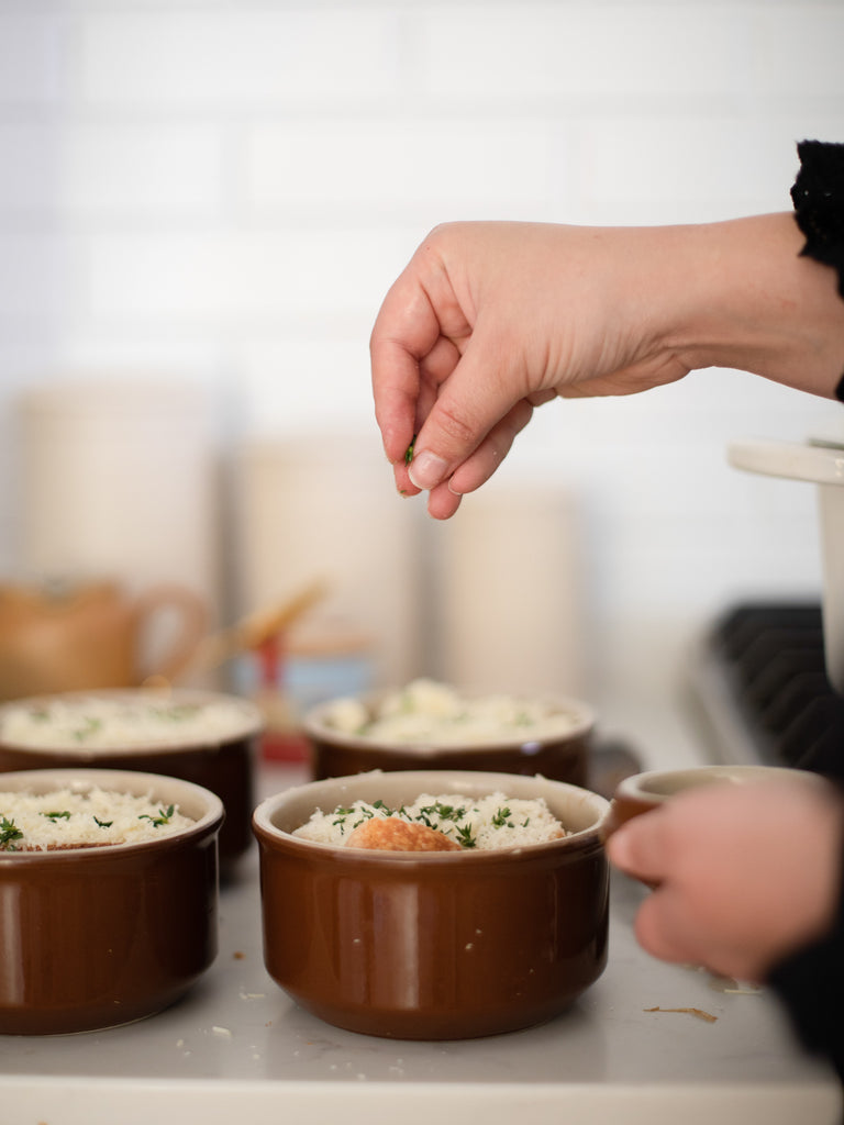 A person using small circle shaped dishes to bake something. 