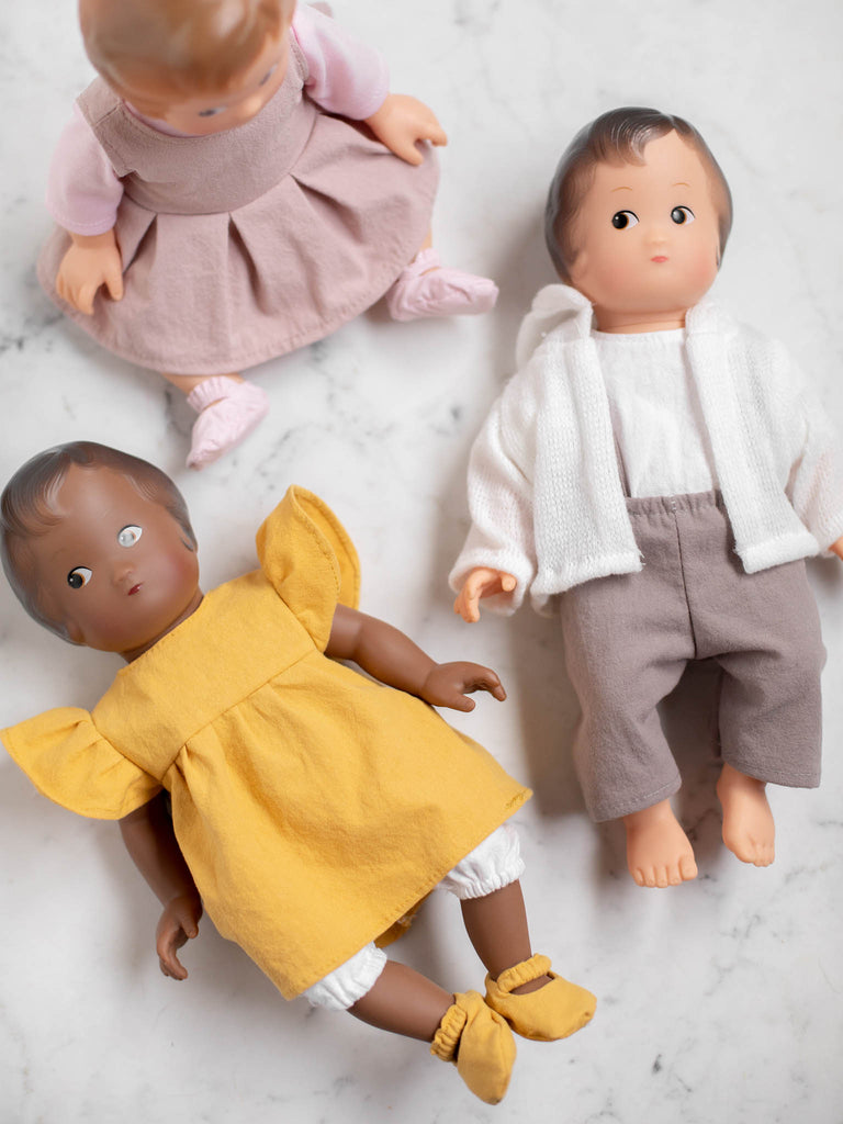 Three vintage baby dolls laid out stylistically on a quartz backdrop. 