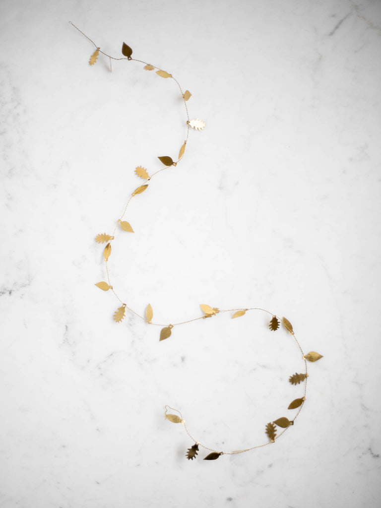 A very thin and bendable piece of brass metal with small thin and flat metal leaf shapes attached throughout the length of it.