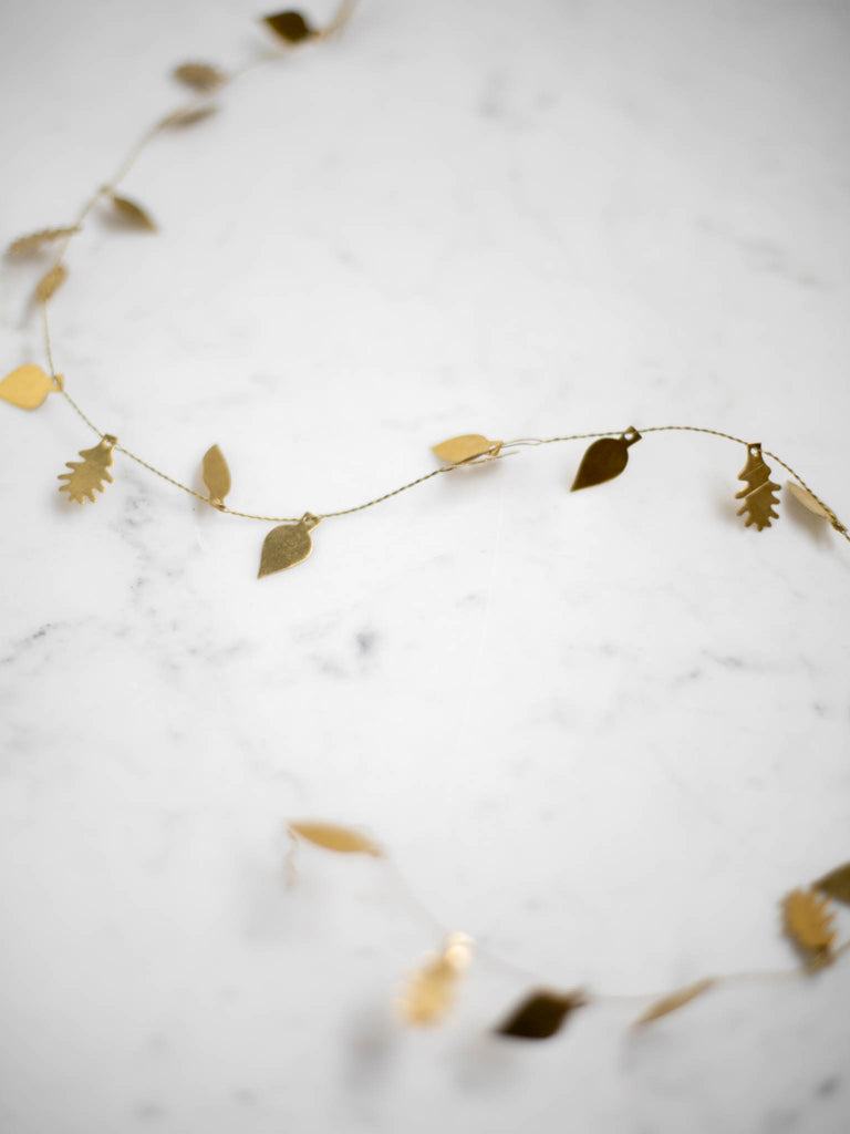 A very thin and bendable piece of brass metal with small thin and flat metal leaf shapes attached throughout the length of it.