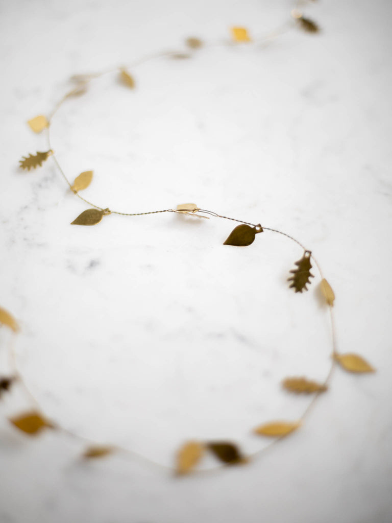 A very thin and bendable piece of brass metal with small thin and flat metal leaf shapes attached throughout the length of it.