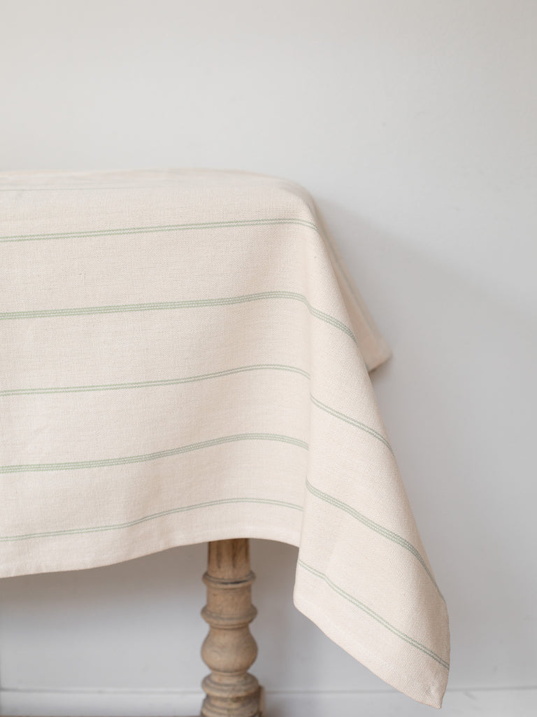 An off-white tablecloth with thin light green stripes.