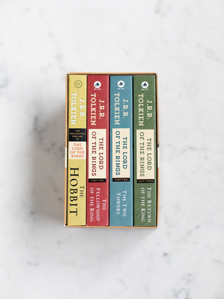 Four multicolored mass market paperback books in a brown box. 