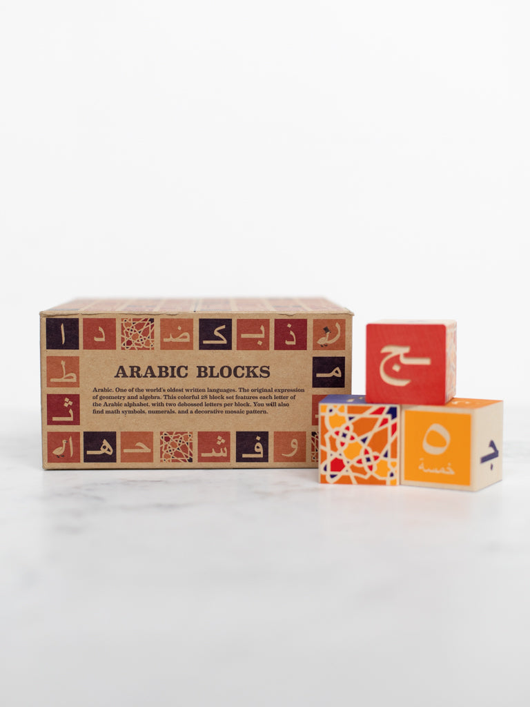 Some blocks decorated with symbols and patterns on their sides with the box they come in behind them titled “Arabic Blocks.”