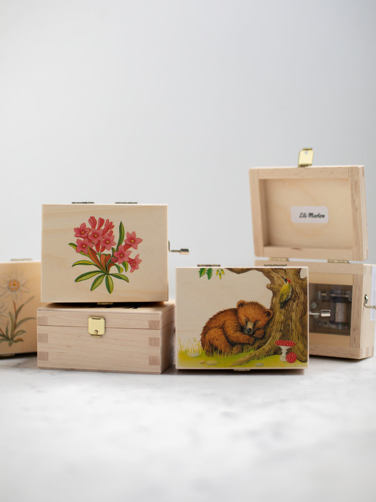 Another stack of alpine music boxes. One features a sleeping bear against a tree trunk with a mushroom on its cover top.