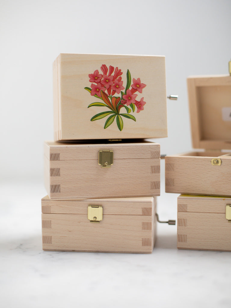 Five music boxes with three stacked directly in view. The top music box has a cover top with a red flower on it.