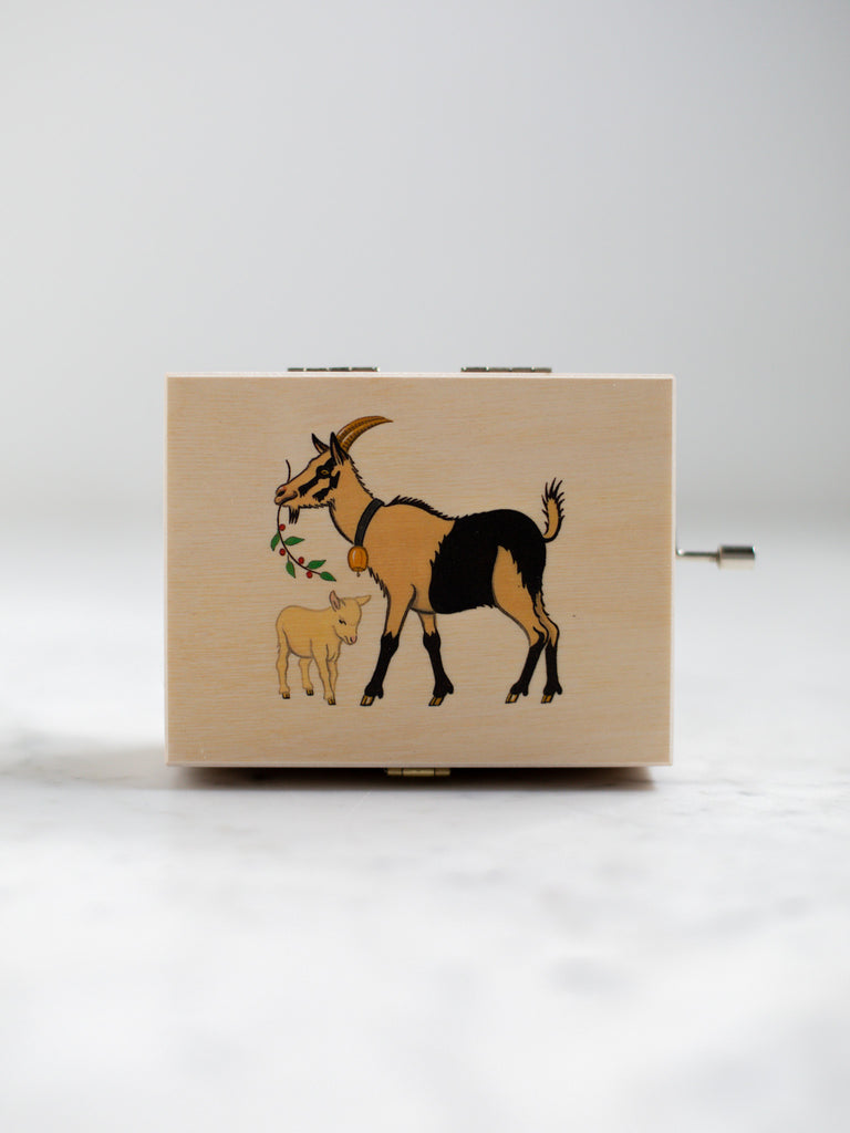 A music box with an alpine goat holding a plant over a baby alpine goat for a cover.