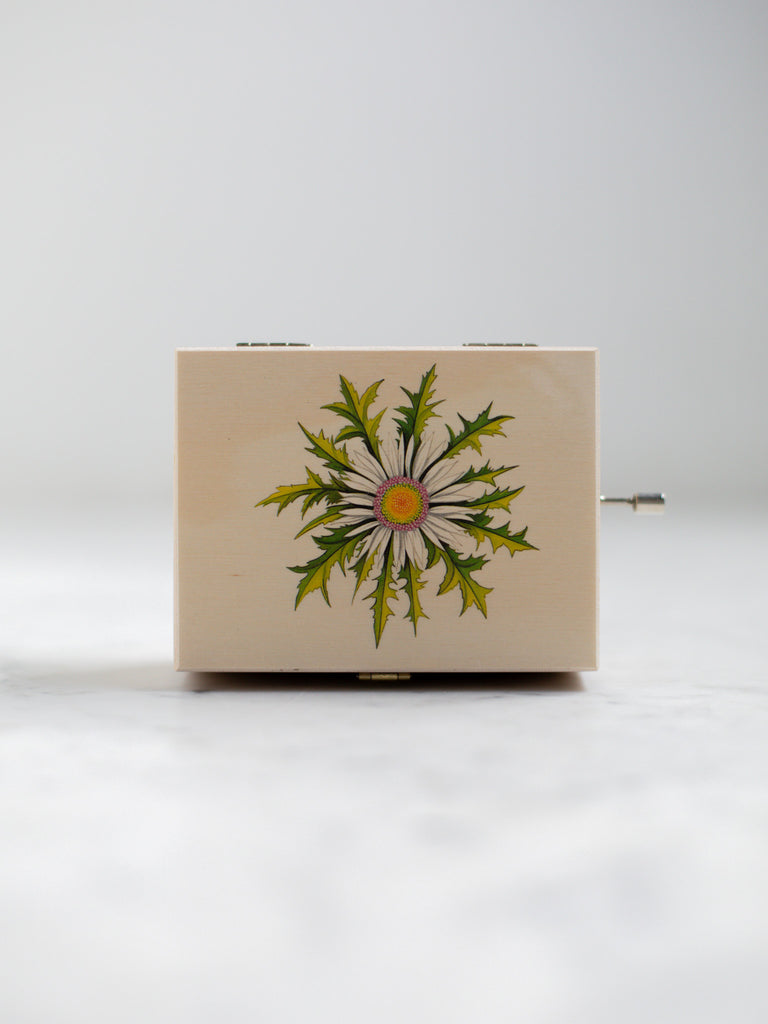 An alpine music box with a white flower on its cover top.
