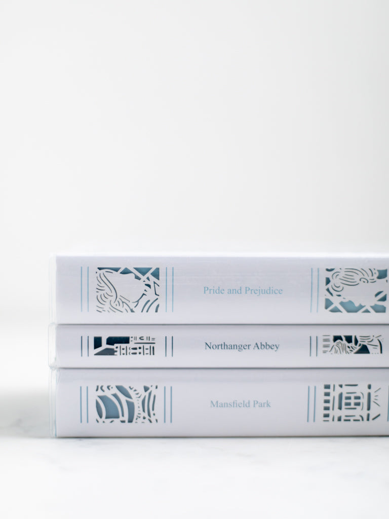 Three books stacked on top of each other with paper cut designs on their spines. 