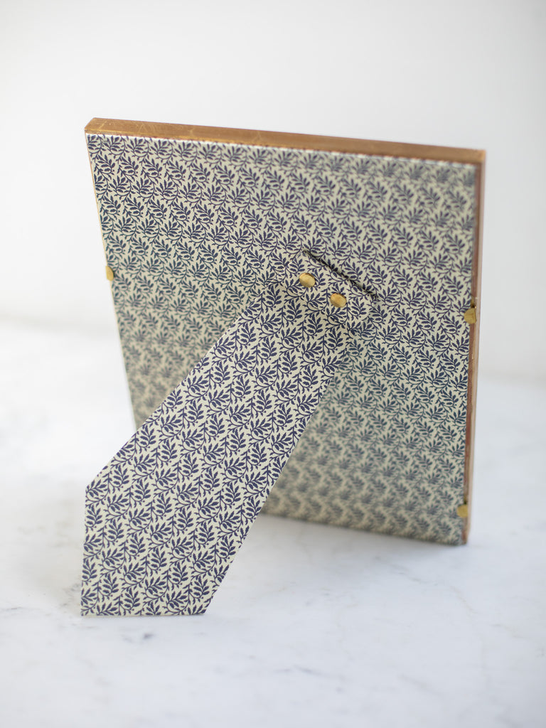 The back of the gold frames, a dark blue leaf batter covering the back of the frame and its stand.