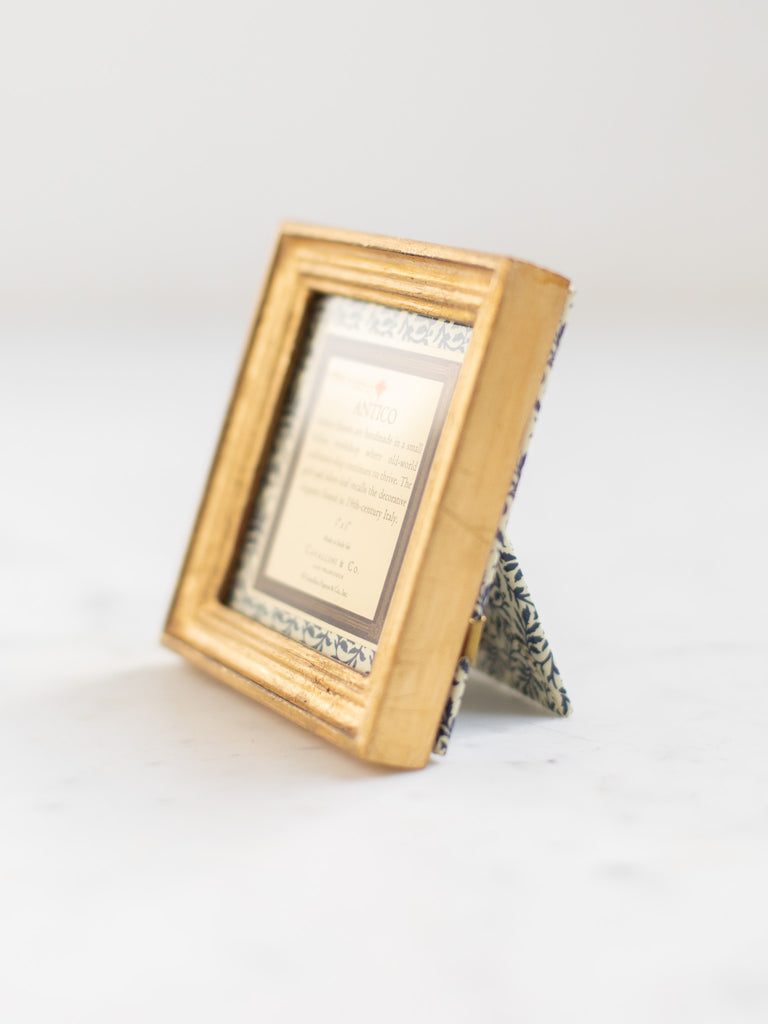 Vintage style gold frames, with a dark blue patterned paper held in the frame, with a description of where the frames are made.