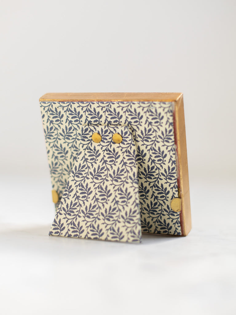 The back of the gold frames, a dark blue leaf batter covering the back of the frame and its stand.