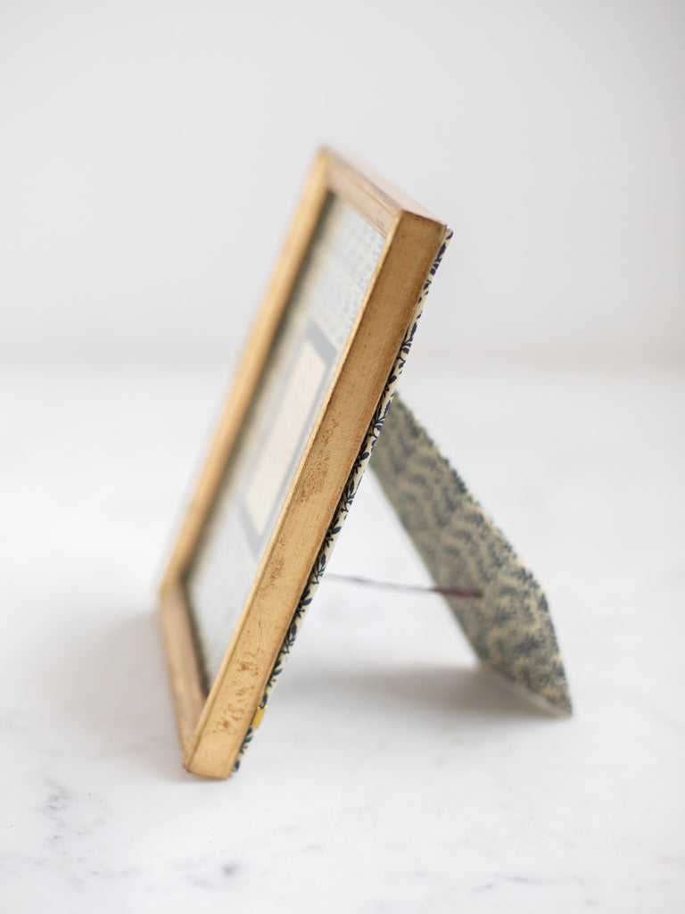Vintage style gold frames, with a dark blue patterned paper held in the frame, with a description of where the frames are made.