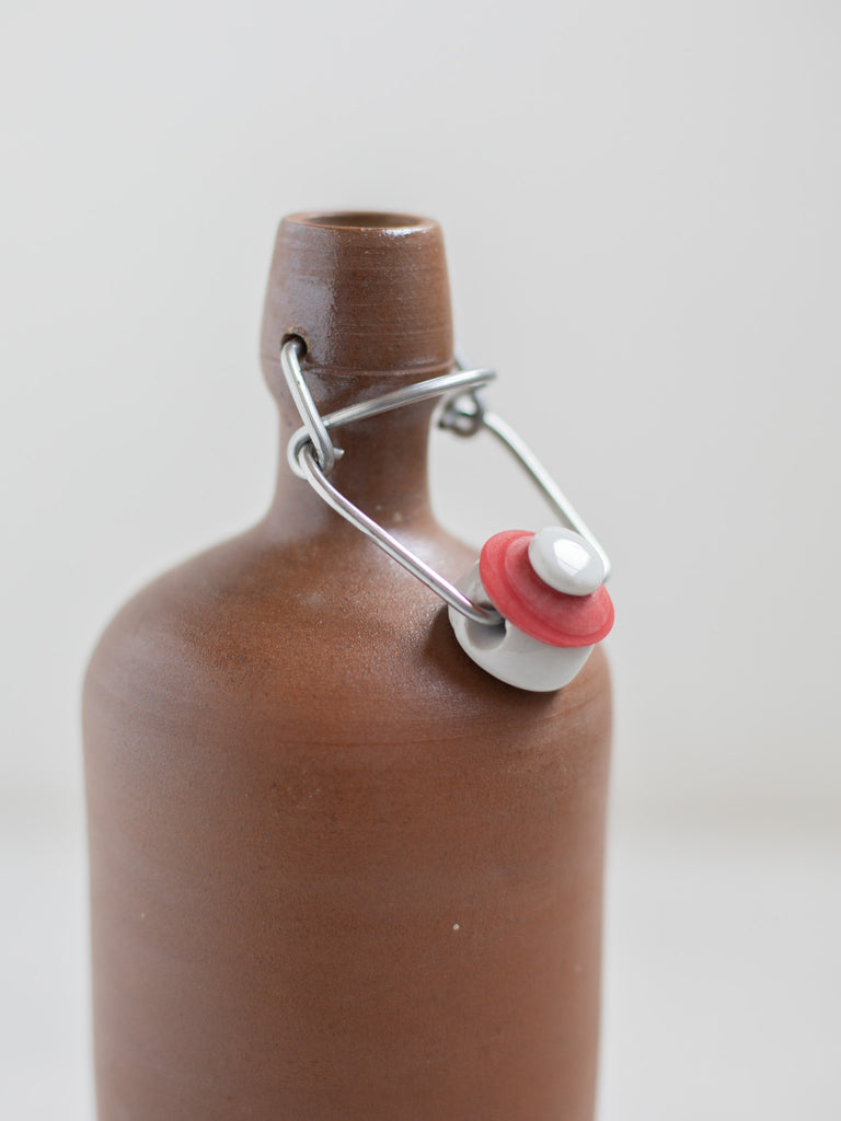 The bottle cap opened on a brown stone bottle. 