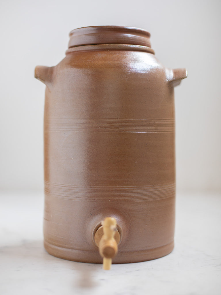 Tall light brown water jug with built in handles. 