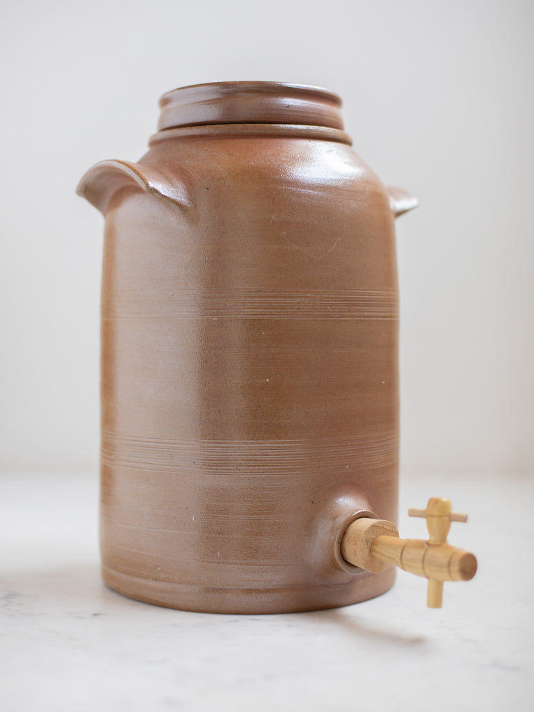 Tall light brown water jug with built in handles. 