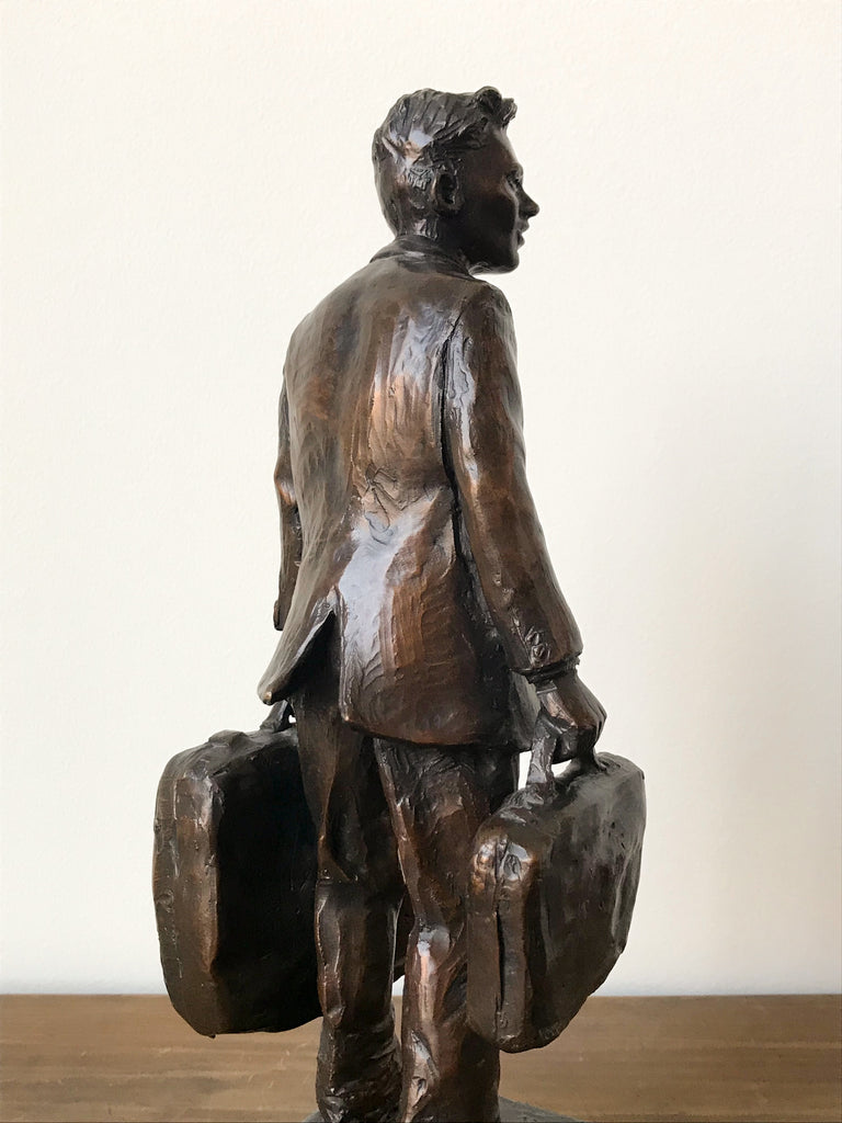 Back view of bronze statue of man with suitcase and briefcase 