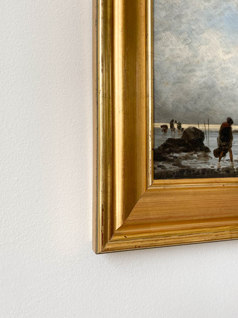 Bottom corner of frame with a view of the subject of the painting, a shaded figure walking along a cloudy beach.
