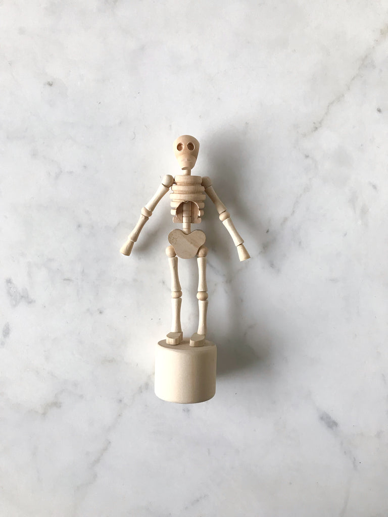 A small wooden movable figure of a skeleton laying on a table. 