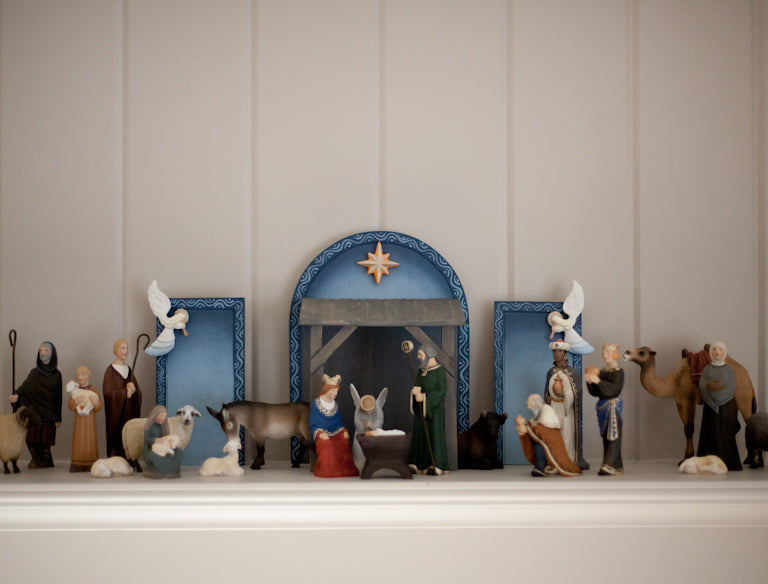 The entirety of the nativity characters positioned in front of a large blue and brown manger background.