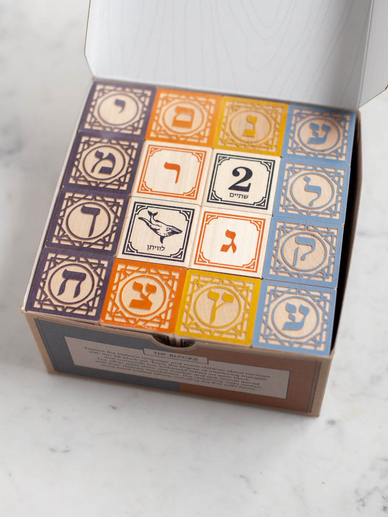 A box opened to reveal lots of multicolored blocks with symbols and animals on them. 