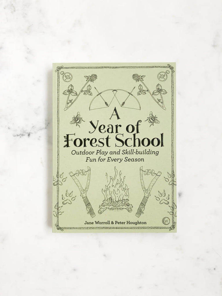 A book titled “A Year of Forest School” with a campfire and s’more sticks, as well as bows and arrows on the cover. 