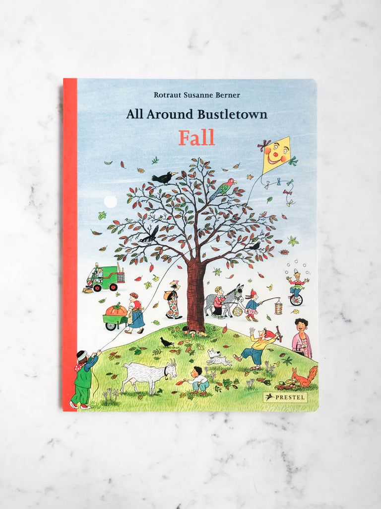 A soft book cover with green and blue entitled “Fall”. The center illustration surrounds a tree with orange and green leaves with falling leaves off to its side. 
