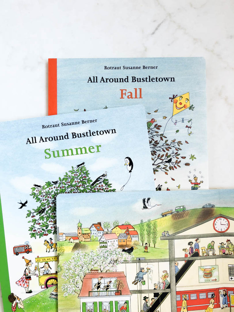 Three books stacked on top of each other. One is “Fall”, another is “Summer”, the third is open face and samples a page. The page has illustrations of homes and apartments.