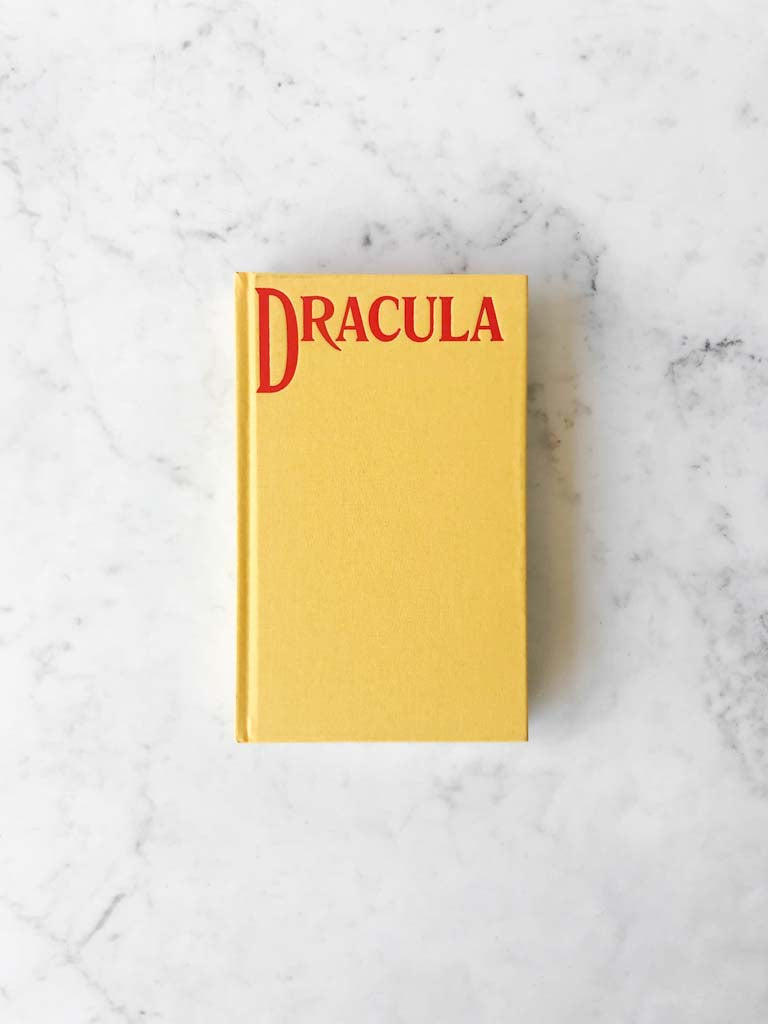 A copy of Dracula. Clothbound yellow book with red lettering at the top. 