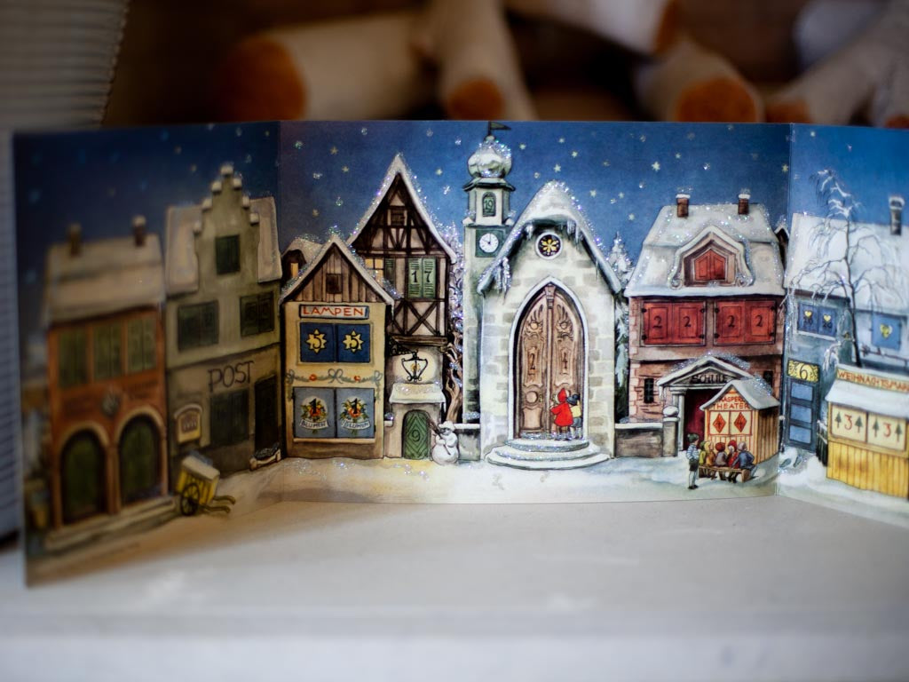 Close up of the Christmas Village paper stand up. Details of a Christmas village are displayed.