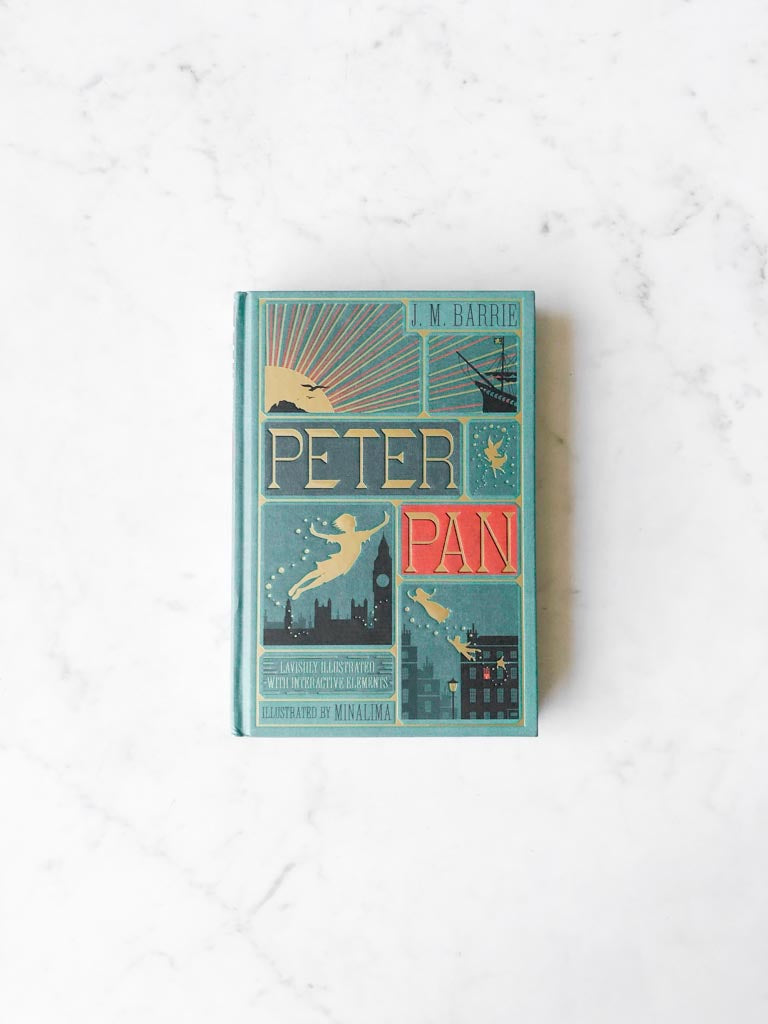 The cover of Peter Pan in blue, with gold colored flying figures of characters and black city building shadows, with the title in a large gold lettered font.