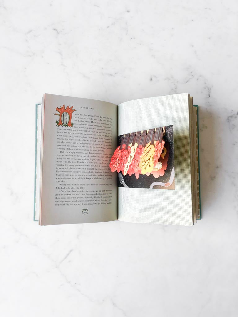 A open page of Peter Pan with words of the story and a folded pop up art.
