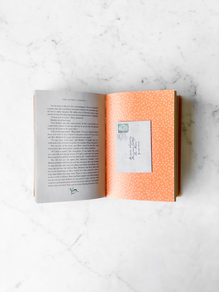 An open page of The Secret Garden with writing of the story and an interactive small addressed letter stuck to the page.