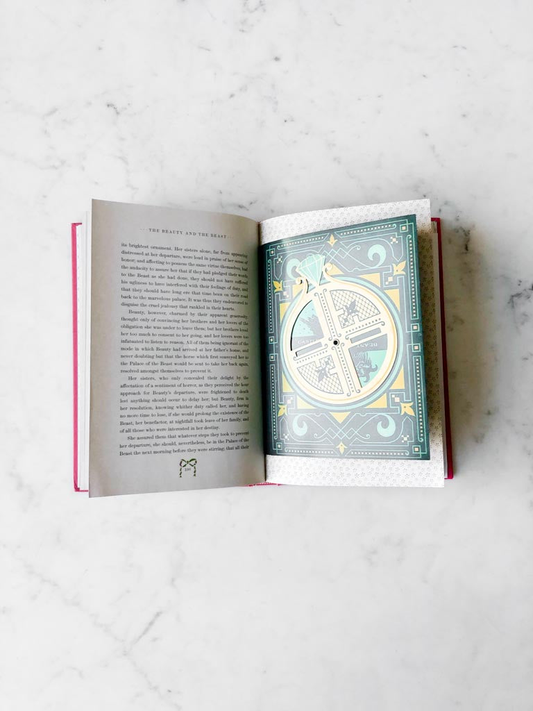 An open page from Beauty and the Beast with writing of the story and an interactive page art design.