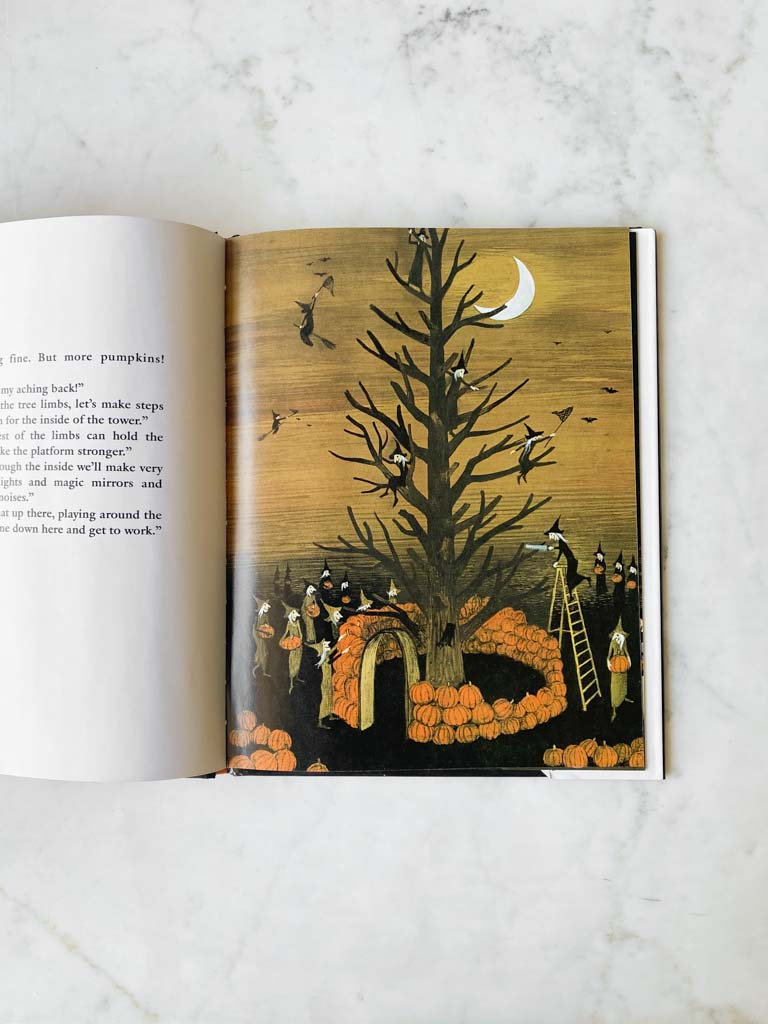 A page from the book showing witches and pumpkins surrounding and hanging from a large and bare tree.
