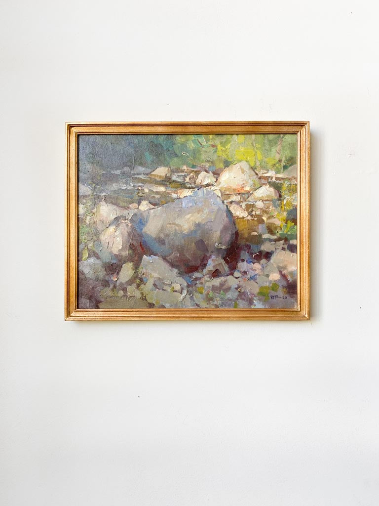 Framed original piece that centers around a creek bed. Features vivid green colors alongside grey pebbles.