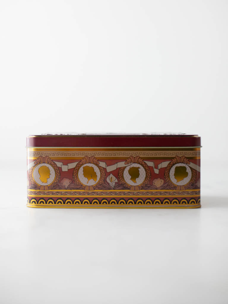 The side of the tin featuring a design of profile faces and ribbon. 