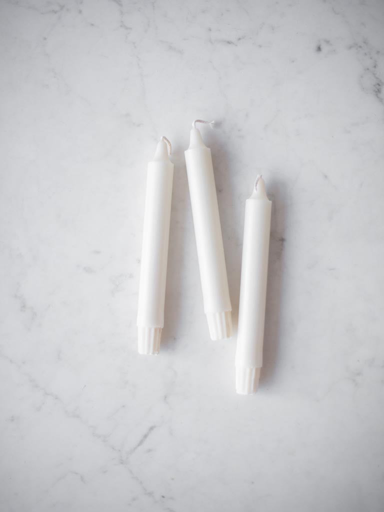 Some white candles on a table. 