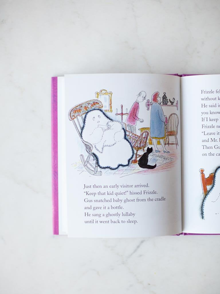 A page from the book, Gus sitting in a rocking chair while holding a baby blanket and feeding it a bottle, while also read it a book. A black cat looks up from the floor while there are human in the background.