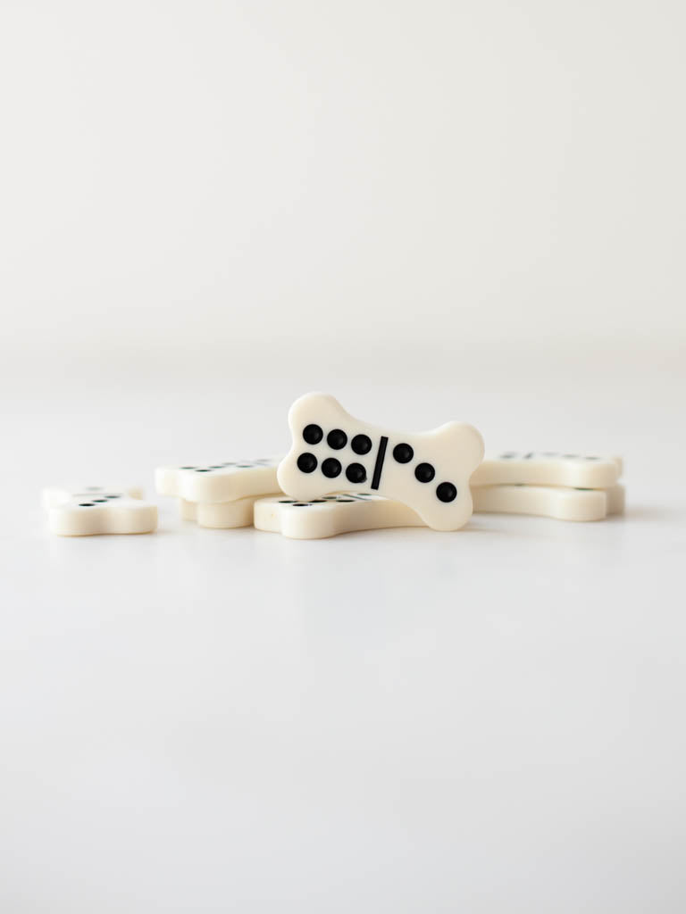 Several bone dominoes laying flat with one bone domino standing up and facing the front.