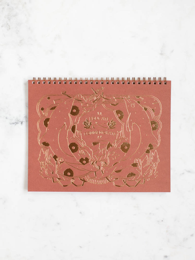 Educate to Commemorate journal cover. Featuring a design with wreaths and two dolphins. 