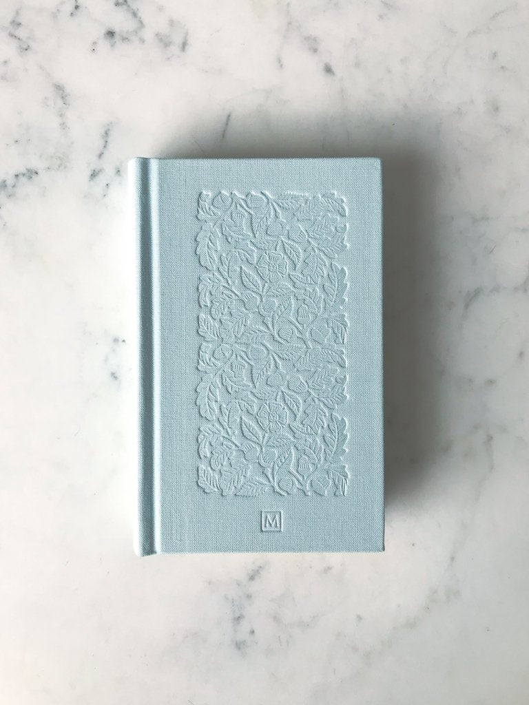 Front view of book without sleeve. Light book with leaf shapes pressed into it.